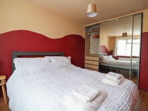 A bedroom with a bed, a wardrobe, and a mirror. - Hafan Deg (Holywell)