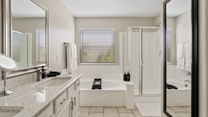 Une salle de bain moderne avec un meuble-lavabo à deux vasques, une baignoire sur pieds, une douche à l’italienne et un grand miroir.