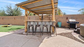 Une terrasse extérieure dotée d’une pergola en bois, d’un barbecue et d’un jacuzzi.