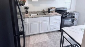 A kitchen with white cabinets, a black refrigerator, a stove, and a sink.