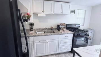A kitchen with white cabinets, a black refrigerator, a stove, and a sink.