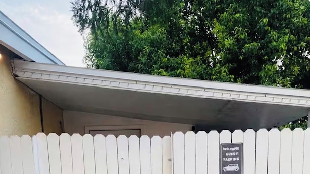 A white picket fence with a sign that reads 'Welcome Guest Parking.'