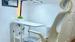 A white office chair with a high backrest and armrests, positioned on a wooden floor.