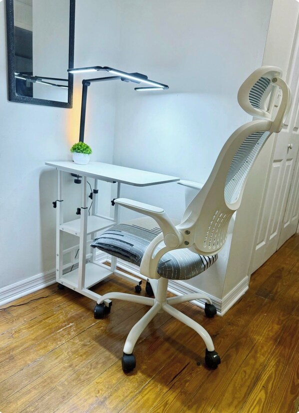 A white office chair with a high backrest and armrests, positioned on a wooden floor.