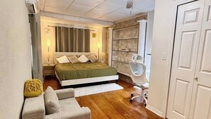 A bedroom with a bed, a chair, a ceiling fan, and a wardrobe.
