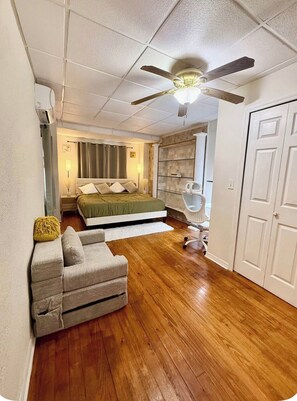 A bedroom with a bed, a chair, a ceiling fan, and a wardrobe.