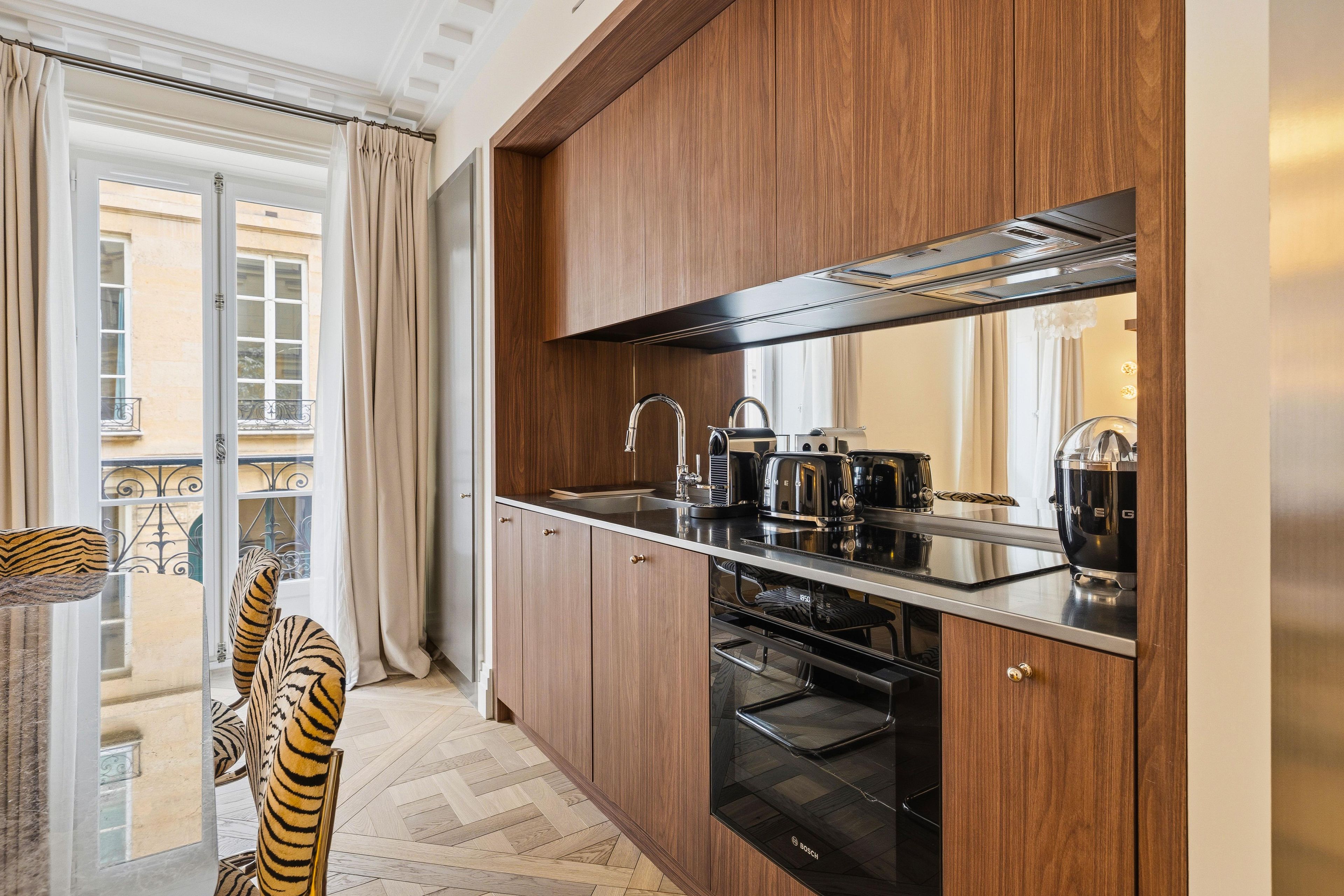 Una cucina moderna con mobili in legno, un forno Bosch e un'ampia finestra con tende.