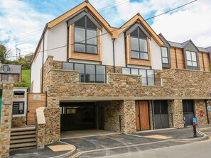A two-story building with a stone facade, large windows, and a garage entrance. - Beachstone (Salcombe)
