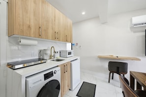 A modern kitchen with wooden cabinets, a built-in microwave, a coffee machine, and a dishwasher.