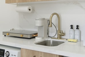 A kitchen with a coffee maker, a sink, and dish soap.