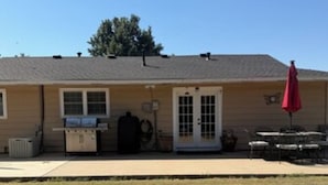 A single-story building with a front door, a small porch, and a red umbrella. - 4-bedroom estate with AC in lovely Enid (Enid)