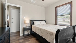 Ein Schlafzimmer mit Bett, Nachttisch, Lampe und Deckenventilator.