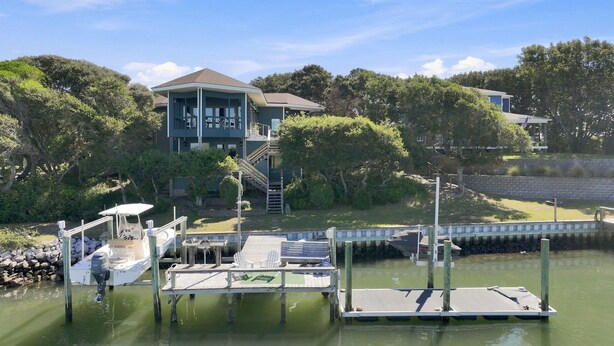 A dock with a boat, a house with a balcony, and a bridge in the background. - Waterfront - Deepwater with dock! 4BR - Near Coast Guard at The Pointe - DOGS OK (Emerald Isle)