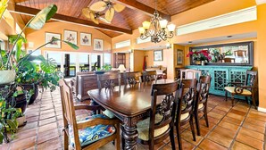 A spacious dining area with a large wooden table and chairs, surrounded by potted plants and artwork on the walls. - Waterfront - Deepwater with dock! 4BR - Near Coast Guard at The Pointe - DOGS OK (Emerald Isle)