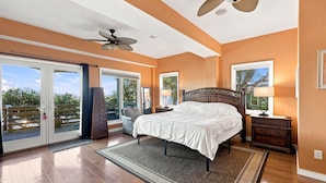 A bedroom with a large bed, a ceiling fan, and a view through the glass doors. - Waterfront - Deepwater with dock! 4BR - Near Coast Guard at The Pointe - DOGS OK (Emerald Isle)