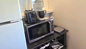 A compact kitchenette with a refrigerator, microwave, toaster, and coffee maker. - The Tidy Third Floor Studio (Buffalo)