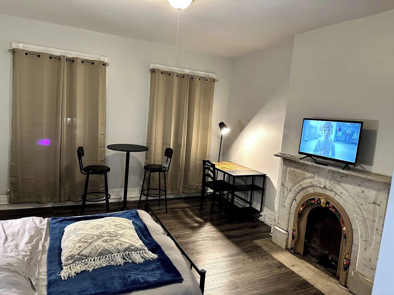 Habitación de hotel con cama, escritorio, dos sillas, televisión y chimenea.