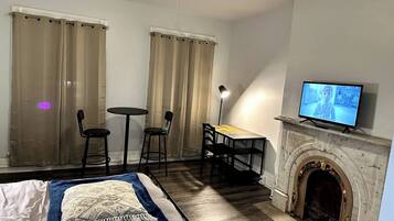 Habitación de hotel con cama, escritorio, dos sillas, televisión y chimenea.