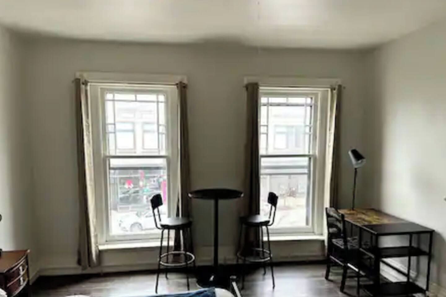 Una habitación con dos ventanas, una mesa, dos sillas y una lámpara de pie.