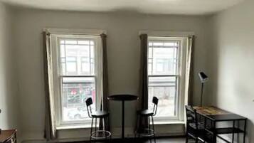 Una habitación con dos ventanas, una mesa, dos sillas y una lámpara de pie.