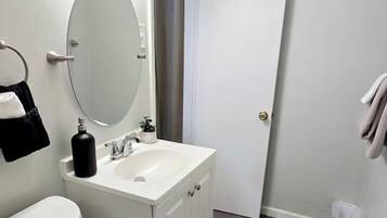 Un baño con inodoro, lavabo, espejo y puerta.