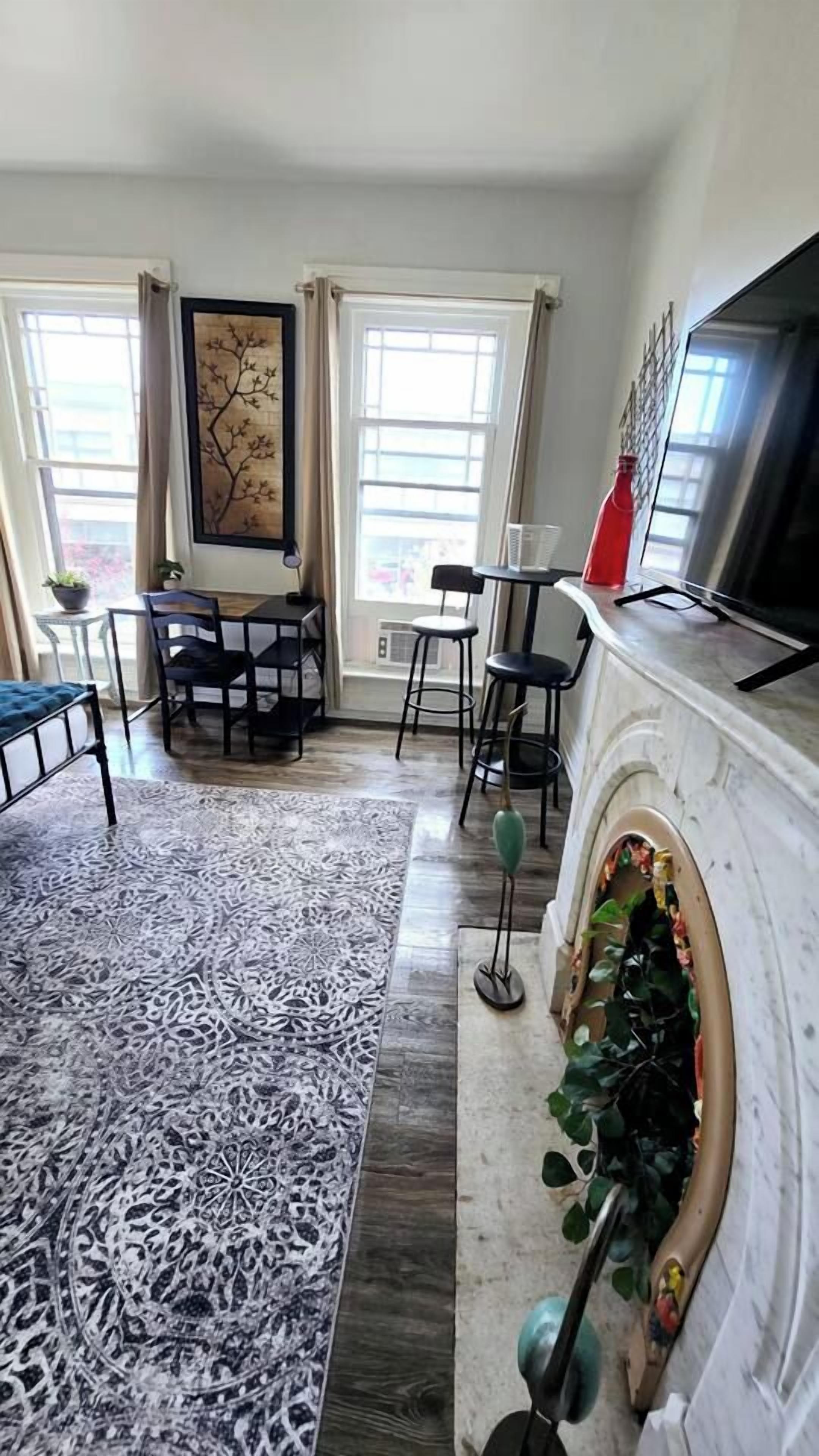 Una sala de estar con chimenea, comedor y un amplio ventanal con cortinas.