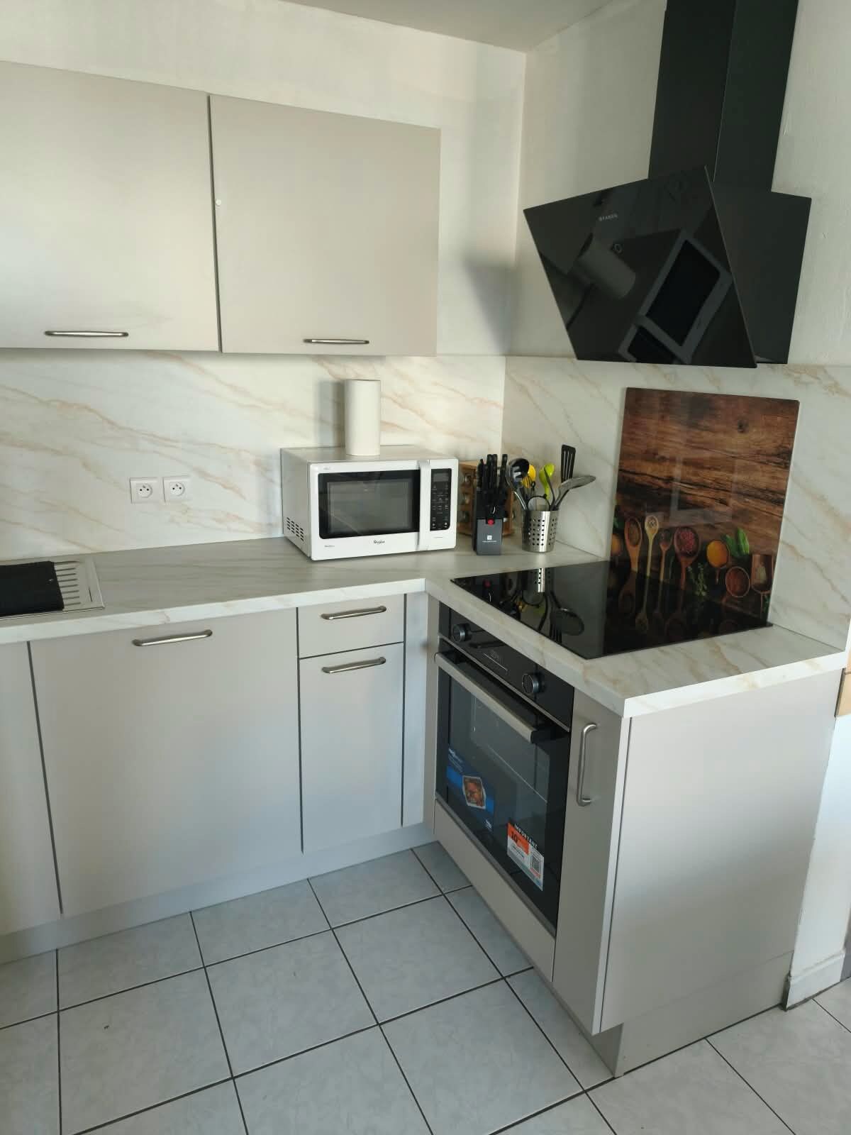 A modern kitchen with white cabinetry, a microwave, an oven, and a black range hood.