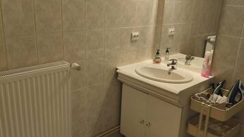 Ein Badezimmer mit einem weißen Waschbecken, einem Spiegel, einem Handtuchhalter und einer Heizung.