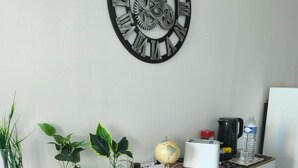 A kitchen counter with a clock, plants, a globe, and kitchen appliances.