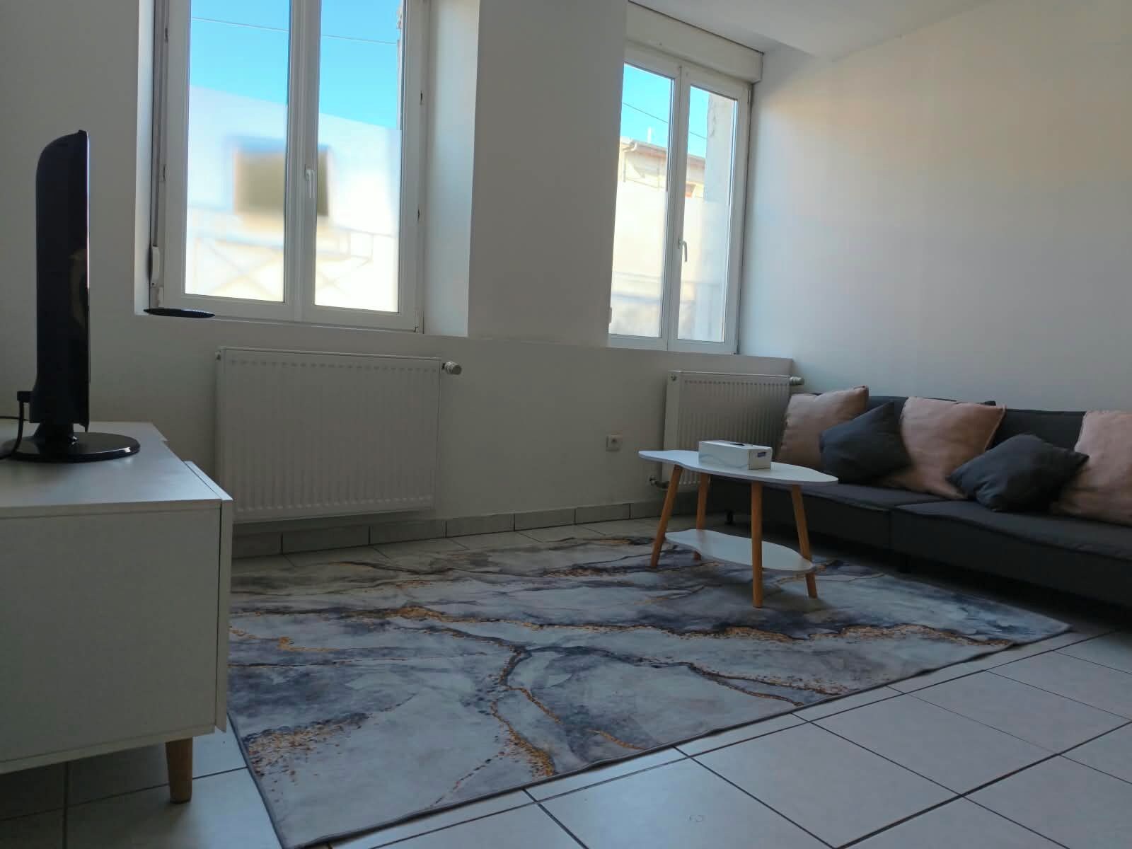 Una sala de estar con un sofá, una mesa de centro y un televisor sobre un mueble.