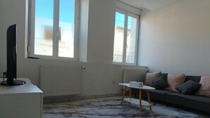 A living room with a sofa, a coffee table, and a TV on a stand. - Vrbo Property (Château-Salins)