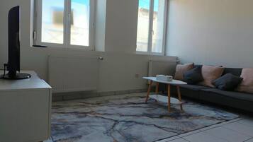 Una sala de estar con un sofá, una mesa de centro y un televisor sobre un mueble.