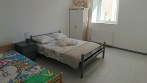 A bedroom with a single bed, a nightstand, a wardrobe, and a window with curtains. - Vrbo Property (Château-Salins)
