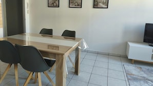 A room with a wooden dining table, four chairs, a white cabinet, and three framed pictures on the wall. - Vrbo Property (Château-Salins)