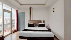 A hotel room with a large bed, a view of the city, and a balcony with a red curtain. - Super Collection O Vaishno Devi Temple (Katra)
