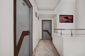Un pasillo con piso de mármol, una puerta con placa de identificación y un cuadro en la pared.