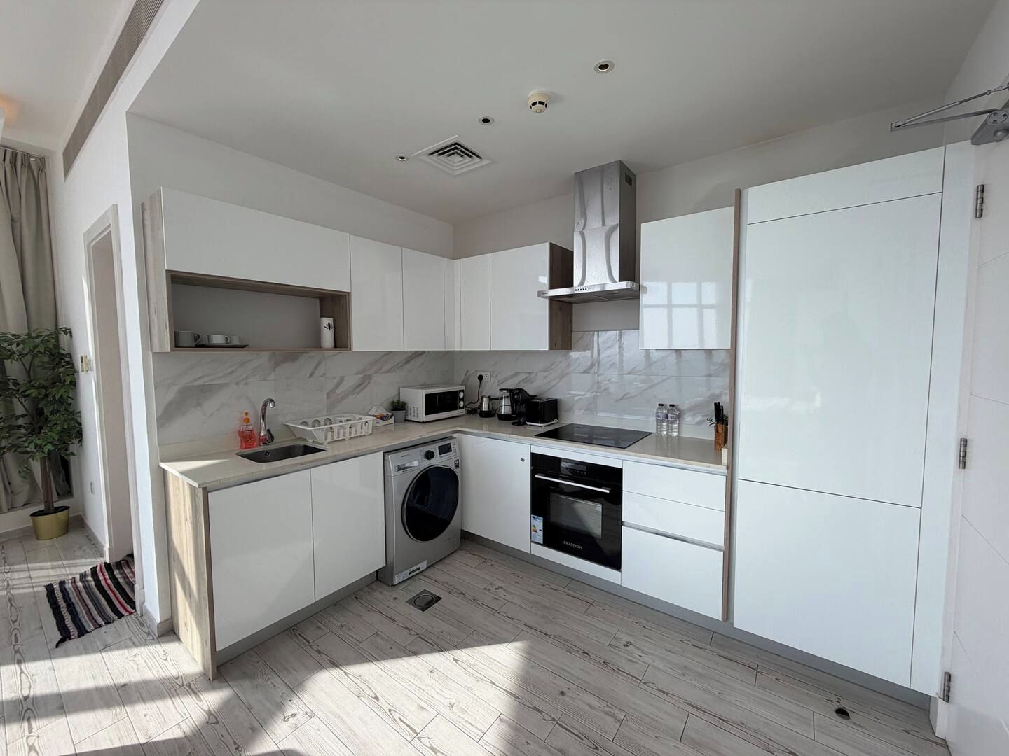 A modern kitchen with white cabinetry, a built-in washing machine, and a microwave.
