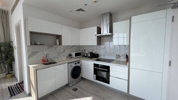 A modern kitchen with white cabinetry, a built-in washing machine, and a microwave.