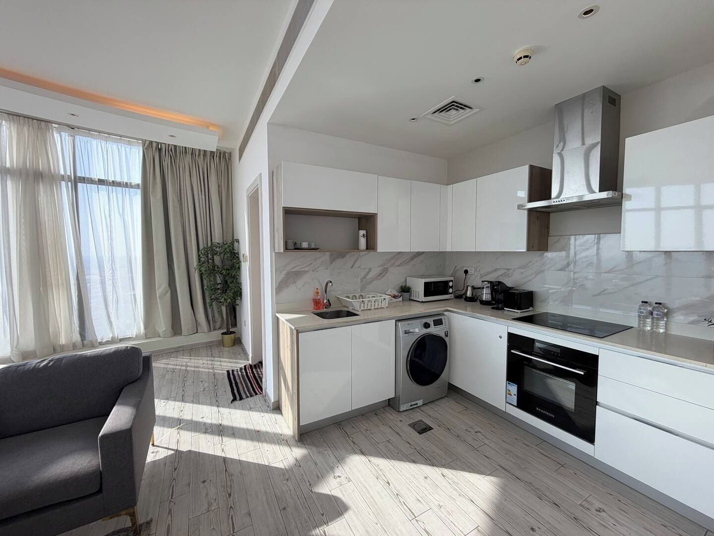 A modern kitchen with a built-in washing machine, a coffee maker, and a microwave.