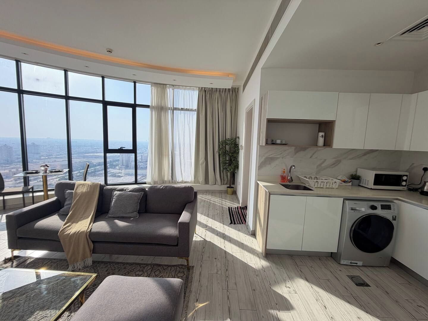 A modern living room with a sofa, a coffee table, and a view of the city through large windows.