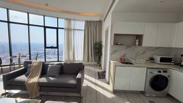 A modern living room with a sofa, a coffee table, and a view of the city through large windows.