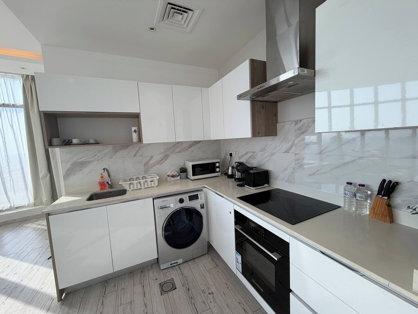 A modern kitchen with a built-in washer, microwave, toaster, and oven.