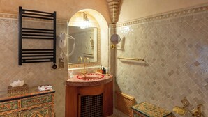 Ein Badezimmer mit Waschtisch, Spiegel, Handtuchhalter und Wandverzierung.