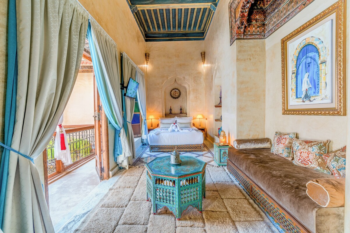 Quarto com cama, sofá, mesinha e parede com quadro emoldurado.