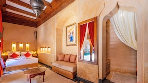 Ein Hotelzimmer mit Bett, Sofa und Blick auf einen Pool durch ein Fenster.