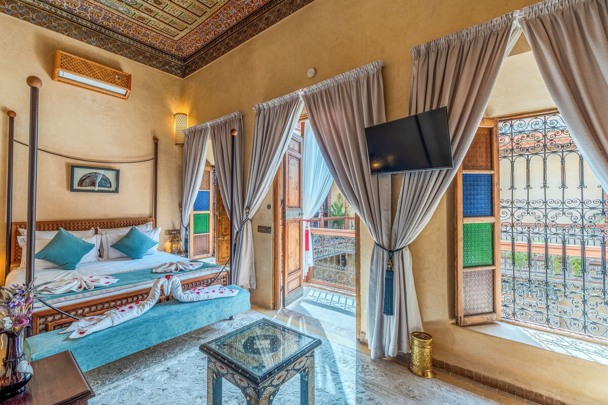 Quarto com cama, televisão e vista para o exterior.