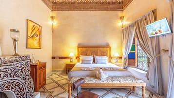 A hotel room with a large bed, a wooden nightstand, a wall-mounted TV, and a patterned floor.