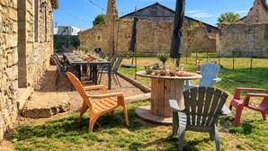An outdoor dining area with stone walls, a wooden table, and chairs. - Cottage de Perseigne (Barville)