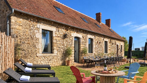 A stone building with outdoor seating, including lounge chairs and a dining table. - Cottage de Perseigne (Barville)