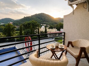 A balcony with a checkered floor, a table with cups and a teapot, and a sofa. - Awecan Radhe Radhe Resort (Qila Kumbhalgarh)